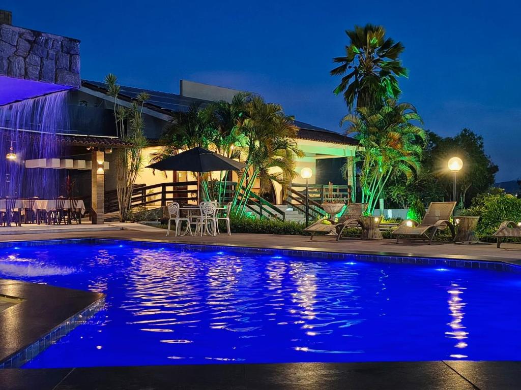 a swimming pool in front of a house at night at Hotel Três Palmeiras in Gravatá