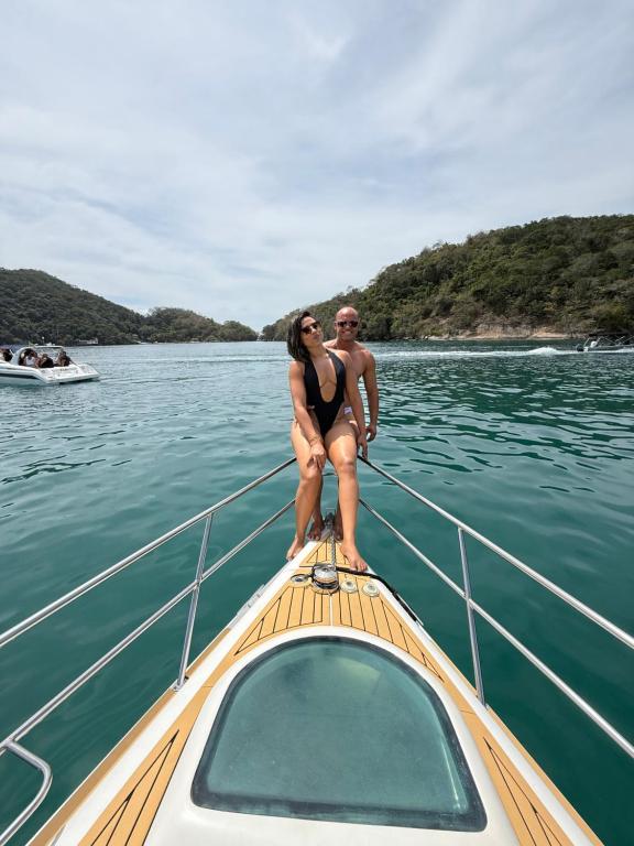 Ein Mann und eine Frau sitzen auf dem Bug eines Bootes in der Unterkunft Aluguel de Lancha em Angra in Angra dos Reis