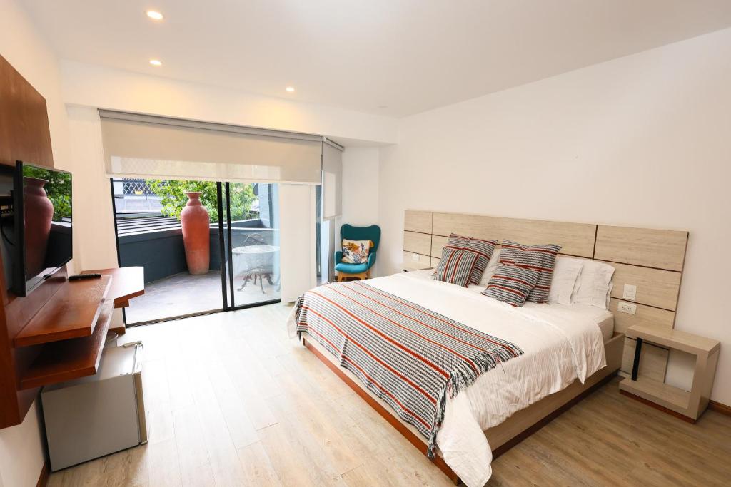 a bedroom with a bed and a desk and a television at Hotel Casa PARDO Boutique in Bogotá