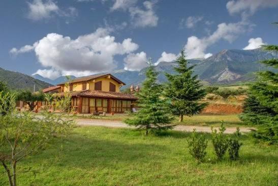 a house in a field with mountains in the background at Agriturismo Conca del Re in Castrovillari