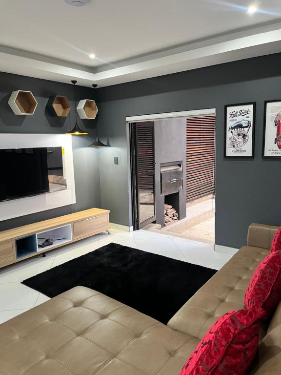 a living room with a couch and a television at 98 Inn Guesthouse Two Bedroom Apartment in Jacksonʼs Drift