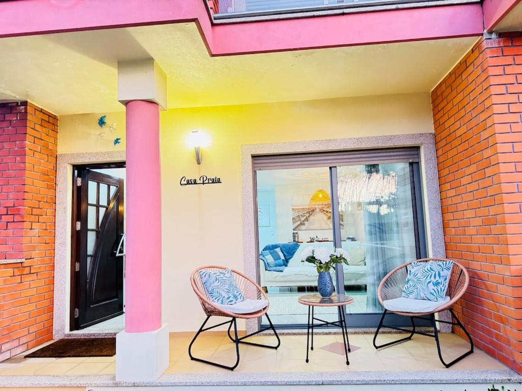 drie stoelen en een tafel voor een gebouw bij Beach House in Fão