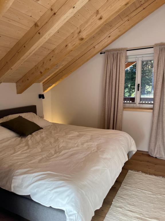 - une chambre avec un grand lit blanc et des plafonds en bois dans l'établissement amKampl-Ferienwohnung, à Radling