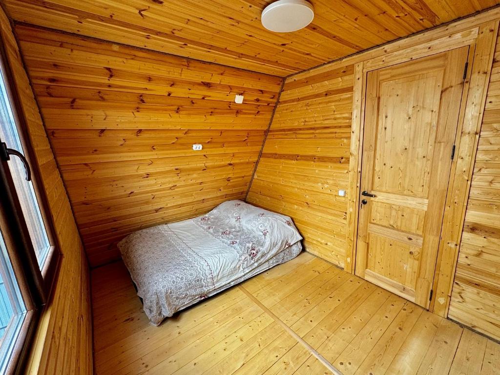 Cette petite chambre comprend un lit dans une cabane en bois. dans l'établissement Cottage in Natakhtari, à Natakhtari
