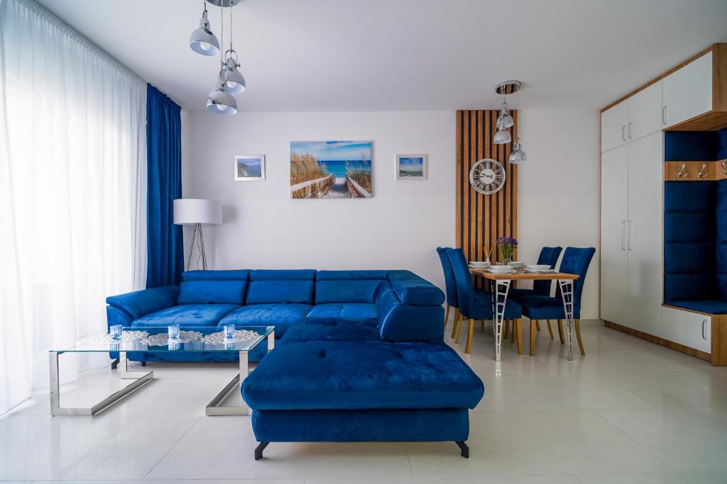 a living room with a blue couch and a table at Lulu Apartments - DEEP BLUE LAGOON apartament dwupokojowy - parking, Netflix - 350m od plaży! in Grzybowo