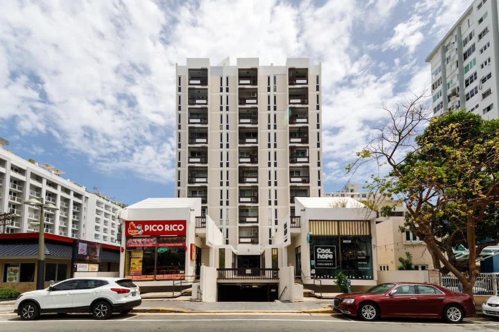 ein hohes weißes Gebäude mit davor geparkt in der Unterkunft ÁMARE | Cozy Beach Studio | Generator | Condado in San Juan