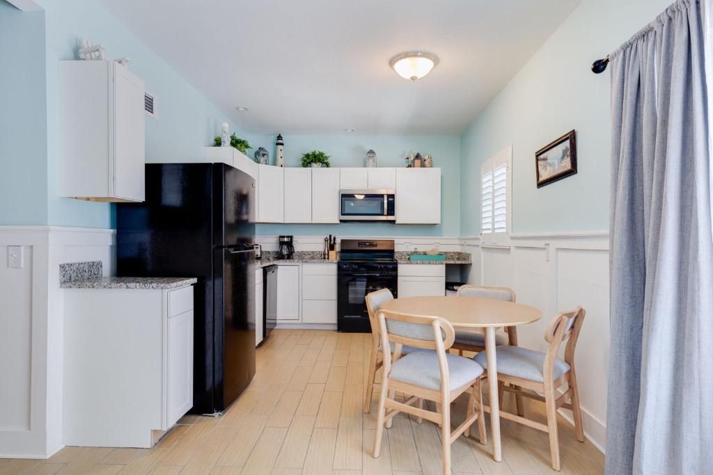 een keuken met witte kasten en een tafel en stoelen bij Gorgeous Apartment on Mango St Steps to Beach in Fort Myers Beach