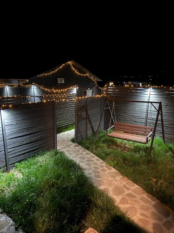 a wooden bench sitting next to a fence at night at Shahdag Berghoff House in Qusar