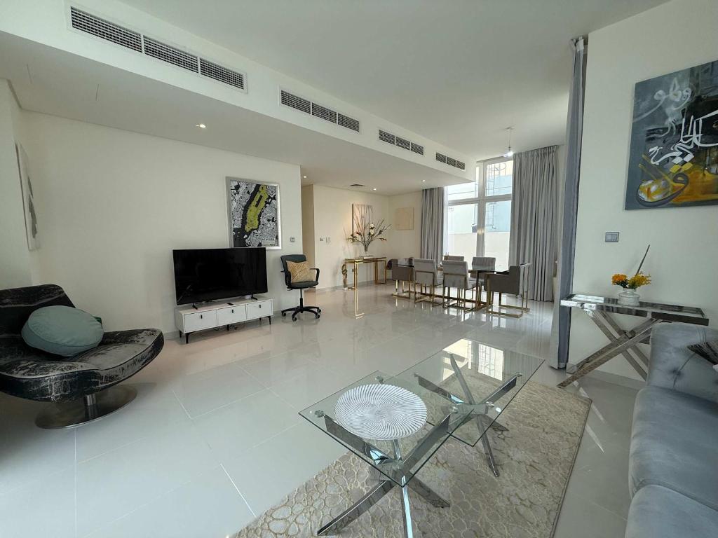 a living room with a couch and a glass table at Spacious Fully Furnished 6BR Villa in Damac Hill2 in ‘Ūd al Bayḑāʼ