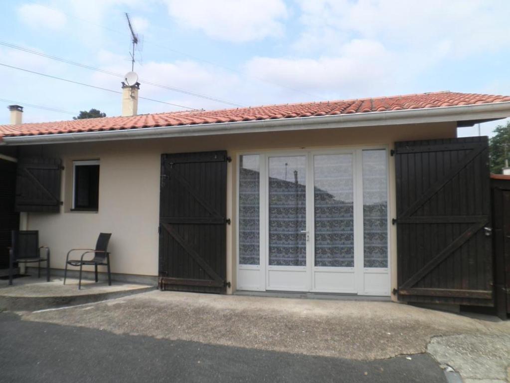 een huis met twee garagedeuren en een stoel bij Le gite de nogaro in Pontonx-sur-lʼAdour