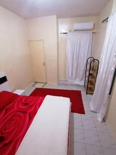 a room with a bed with a red blanket at Résidence hibis chez M&B in Saly Portudal