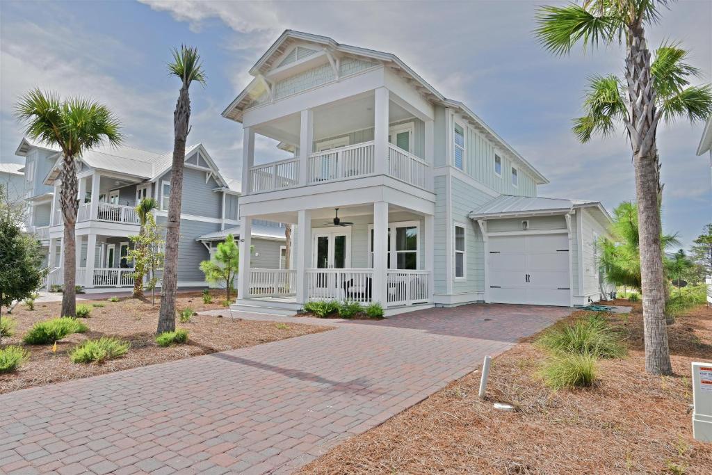 a white house with palm trees and a driveway at Prominence Southside - Blue Skies in Watersound Beach