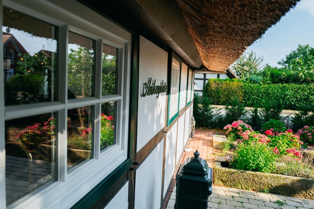 伦布鲁Cottage mit Kamin und Garten, seenah的院子中带窗户和鲜花的建筑