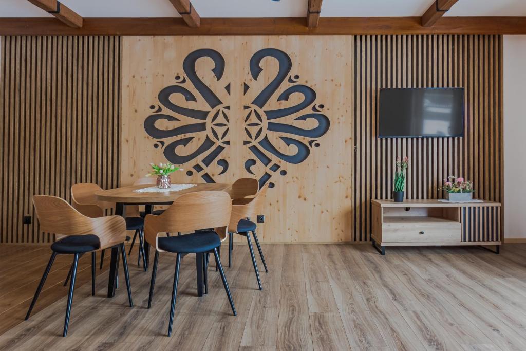 a dining room with a table and chairs and a tv at Cicha Przystań i Cicha Ostoja Komfortowe Domki blisko Term Chochołowskich in Ciche