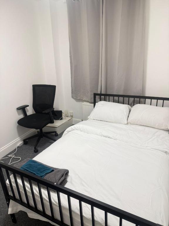a bedroom with a white bed and a chair at Saunders house in Gillingham