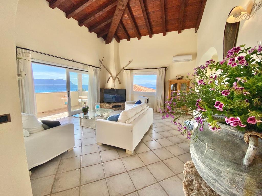 a living room with white furniture and a view of the ocean at Luxury apartment Ginestra sea view with common swimming pool just 50 mt from the beach in Golfo Aranci