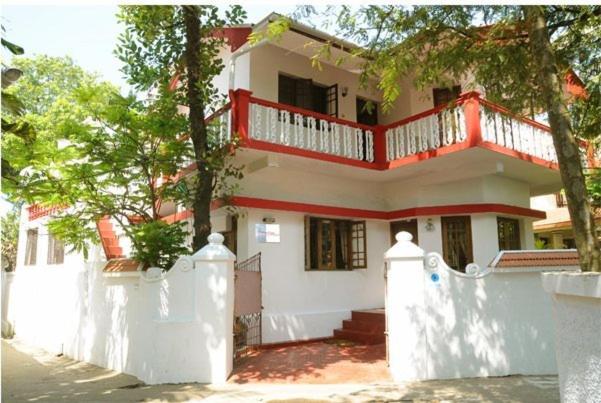a white house with a red balcony on top of it at Maison Casero Home Stay in Cochin