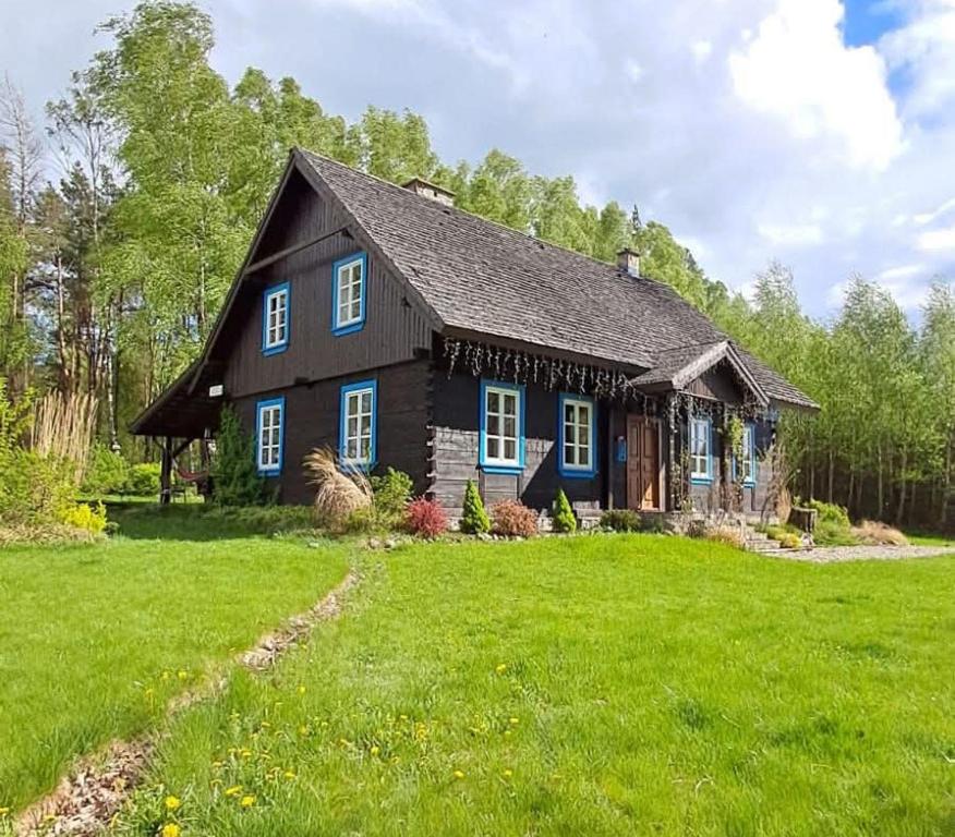 een zwart huis met blauwe ramen en een groene tuin bij SoBądź - Po prostu bądź in Sobącz