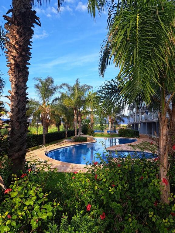 a pool at the resort with palm trees and flowers at kalma in Moncófar