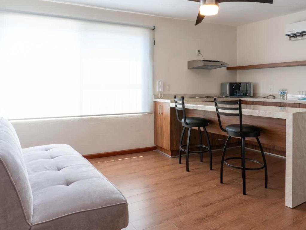 a living room with a kitchen with a bar and chairs at Acogedor Loft en centro histórico - Depa #2 in Isla Cardones