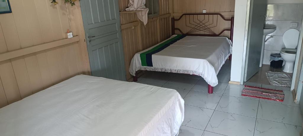 two beds in a small room with a bathroom at Casa de Veraneio in Passo De Torres