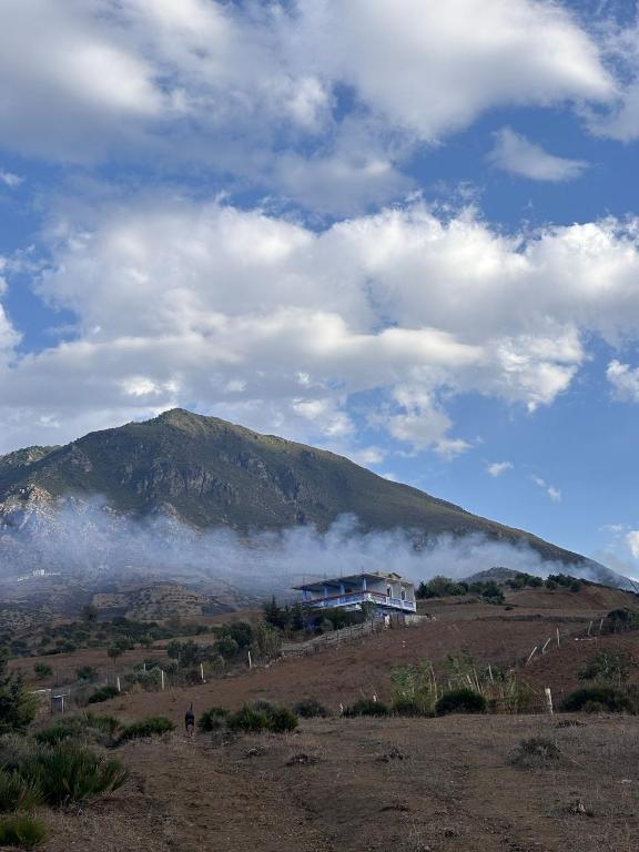 a house on top of a hill with a mountain at Wildhaven Farmstay in Chefchaouen