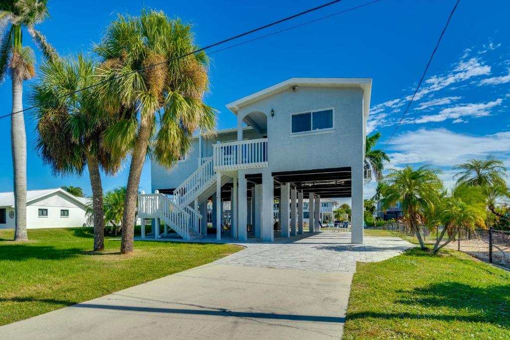 a white house with palm trees and a sidewalk at Boat Dock and Patio Canal-Front St James City Home! in Saint James City