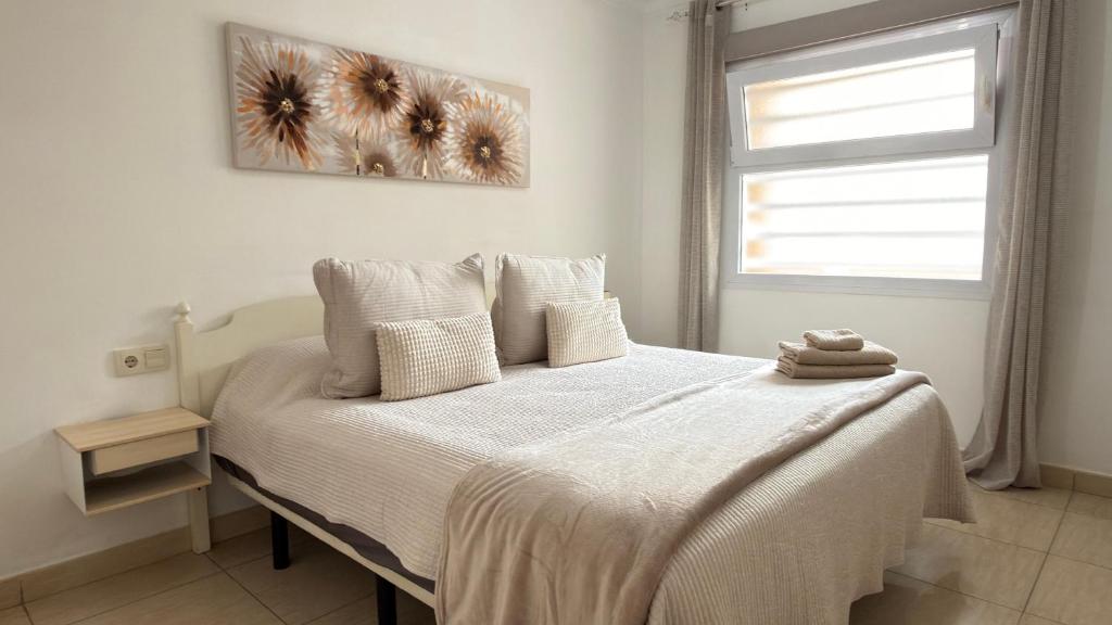 Un dormitorio con una cama con sábanas blancas y una ventana. en central in Los Cristianos Balcony and beach on foot, en Los Cristianos