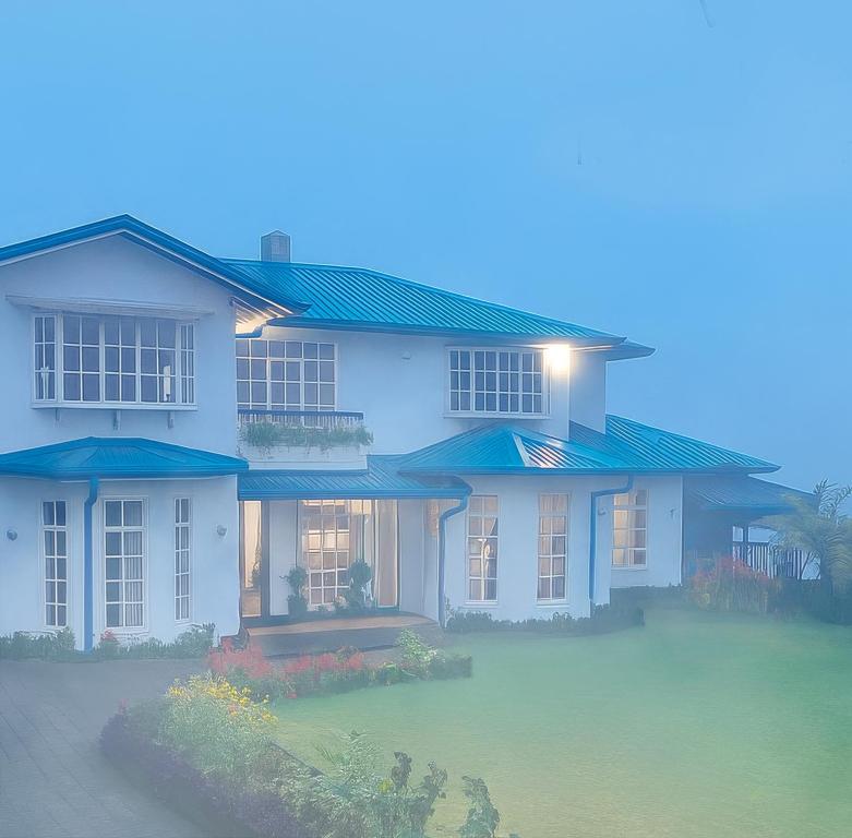 a large white house with blue roofs at Aaradhya Nuwara Eliya in Nuwara Eliya