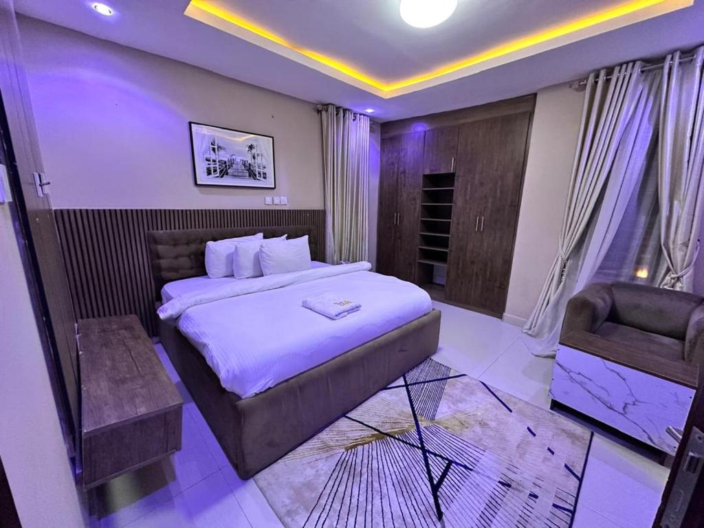 a bedroom with a large bed and a chair at May Gold Luxury Apartments in Benin City