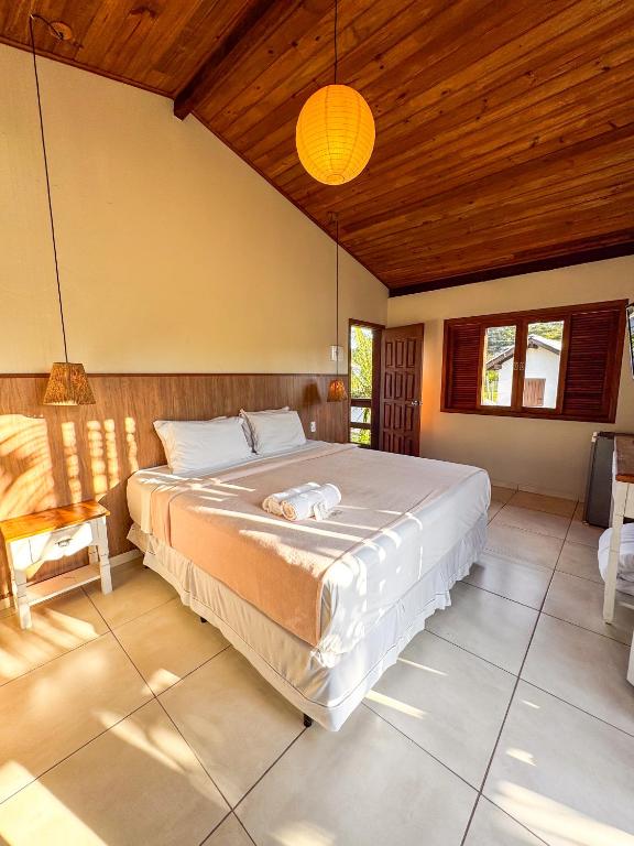 a bedroom with a large bed and a wooden ceiling at Pousada Lagoa do Rosa in Praia do Rosa