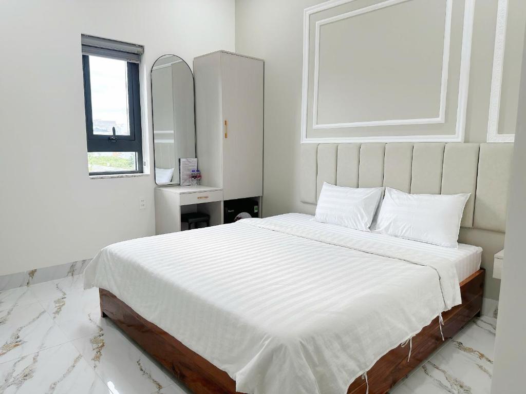 a white bedroom with a large bed with white sheets at Anh Thư Hotel in Ấp Bình Hưng