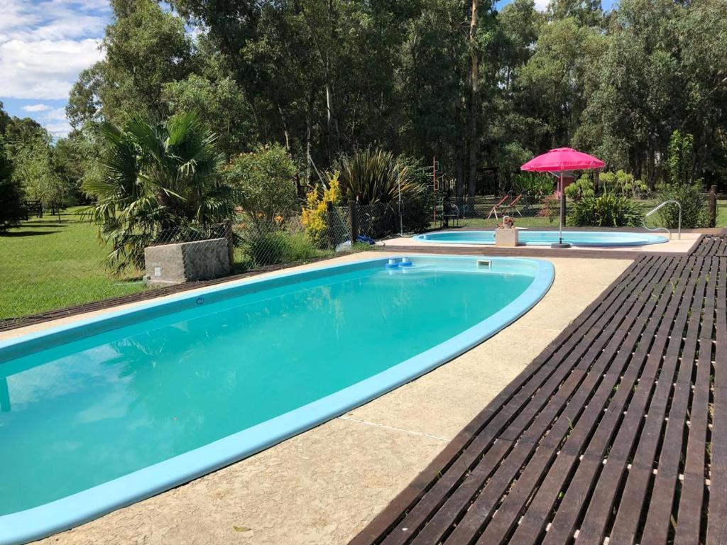 a swimming pool with an umbrella in a yard at Galilea in San Miguel del Monte
