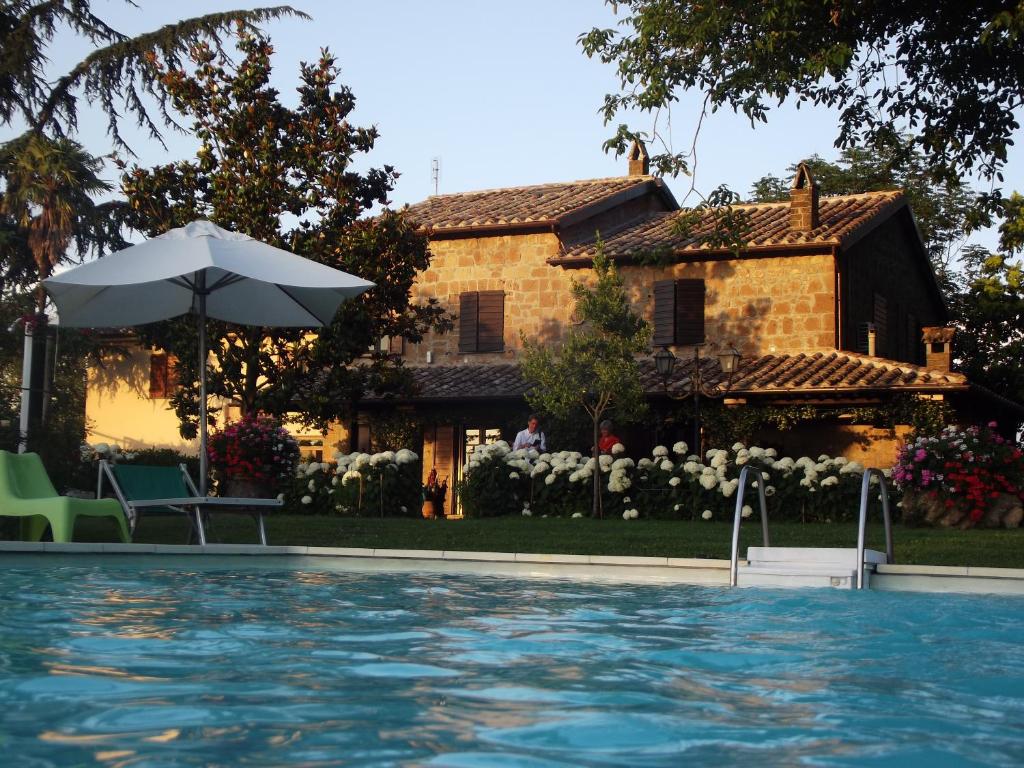 a house with a swimming pool and an umbrella at Podere Sette Piagge in Orvieto
