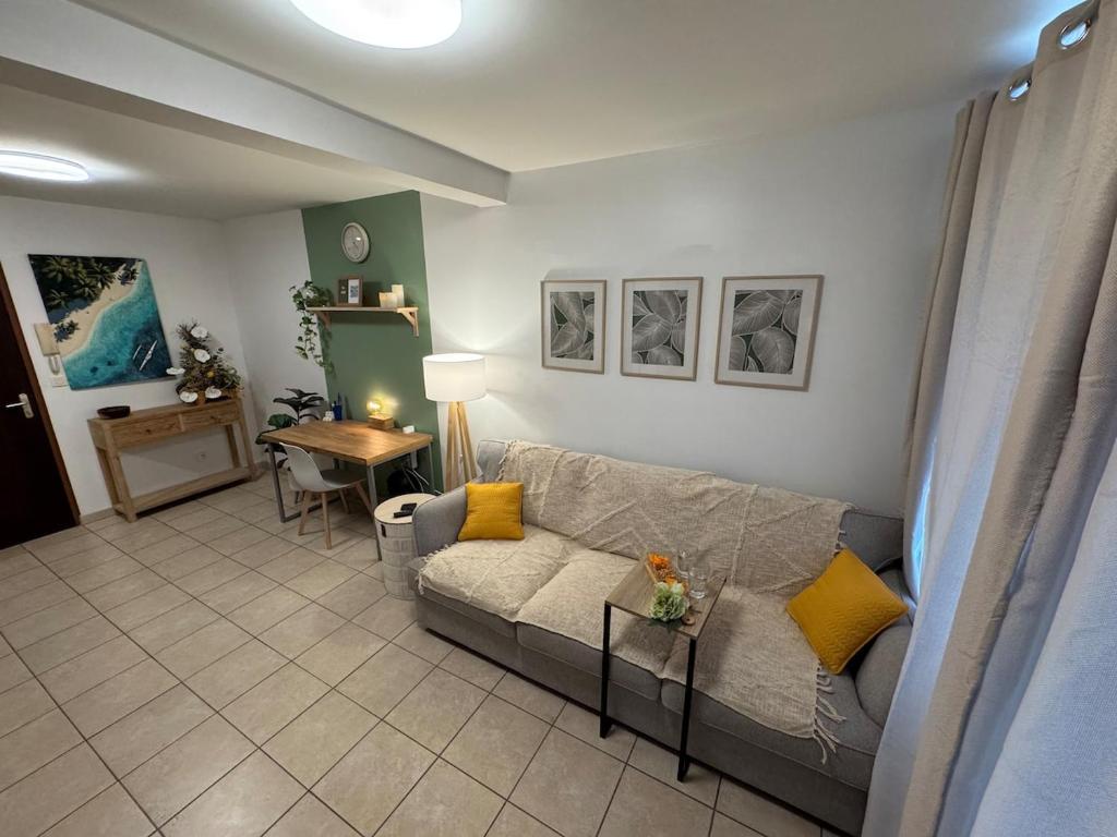 a living room with a couch and a table at Hinahei - Grand F1 with parking 5 min from Papeete in Papeete