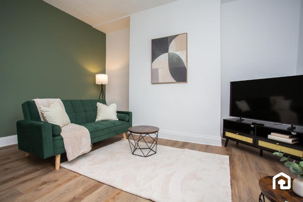 un salon avec un canapé vert et une télévision à écran plat dans l'établissement Jackson Street Wi-fi Parking Vacant Nest, à Tynemouth