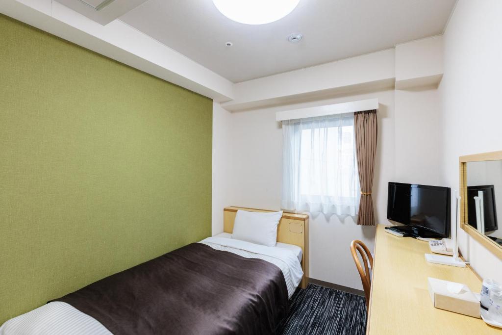 a hotel room with a bed and a desk and a television at Nagoya Sakae Green Hotel in Nagoya