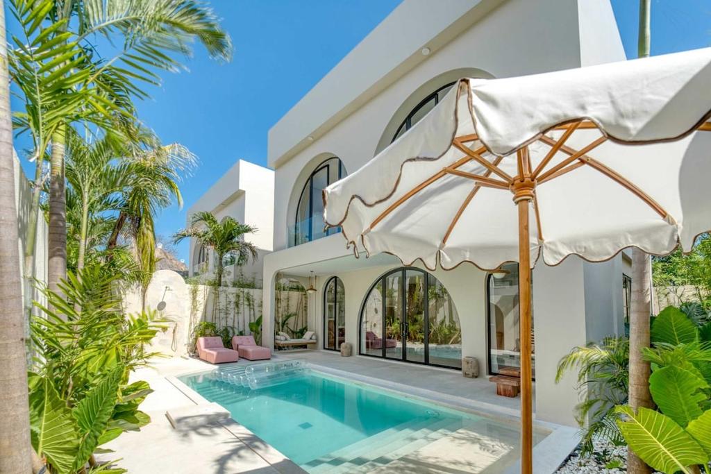 a villa with a swimming pool and an umbrella at Parisian New 2BR Luxury Villa 8mins walk to Beach in Bingin Beach