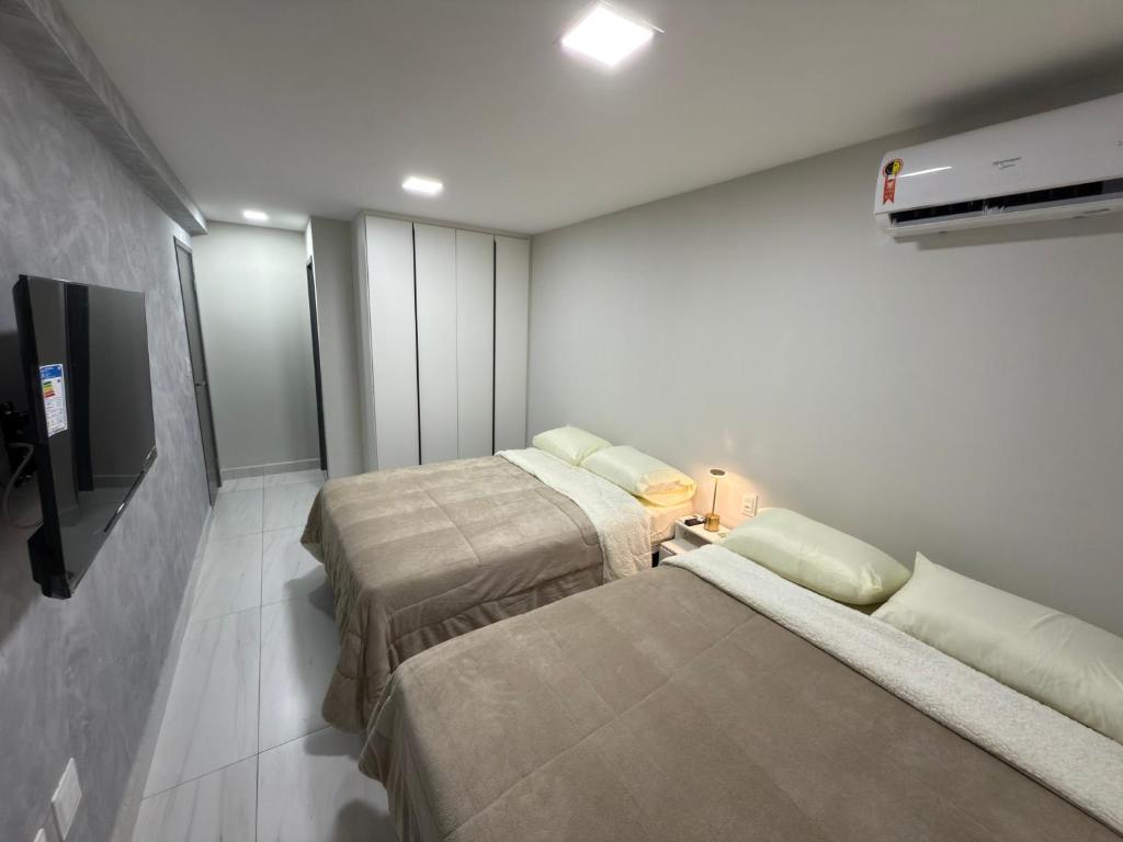 a room with two beds and a flat screen tv at Comfort and elegance in the heart of Cabo Branco in João Pessoa