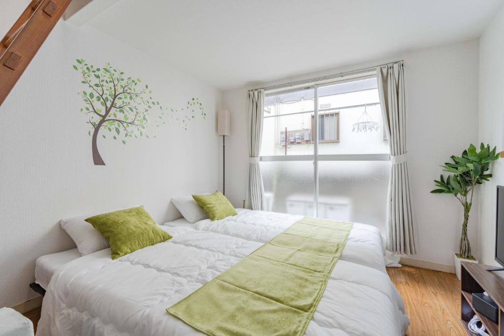 a white bedroom with a large bed with green pillows at Chihaya Relaxation Haven in Fukuoka