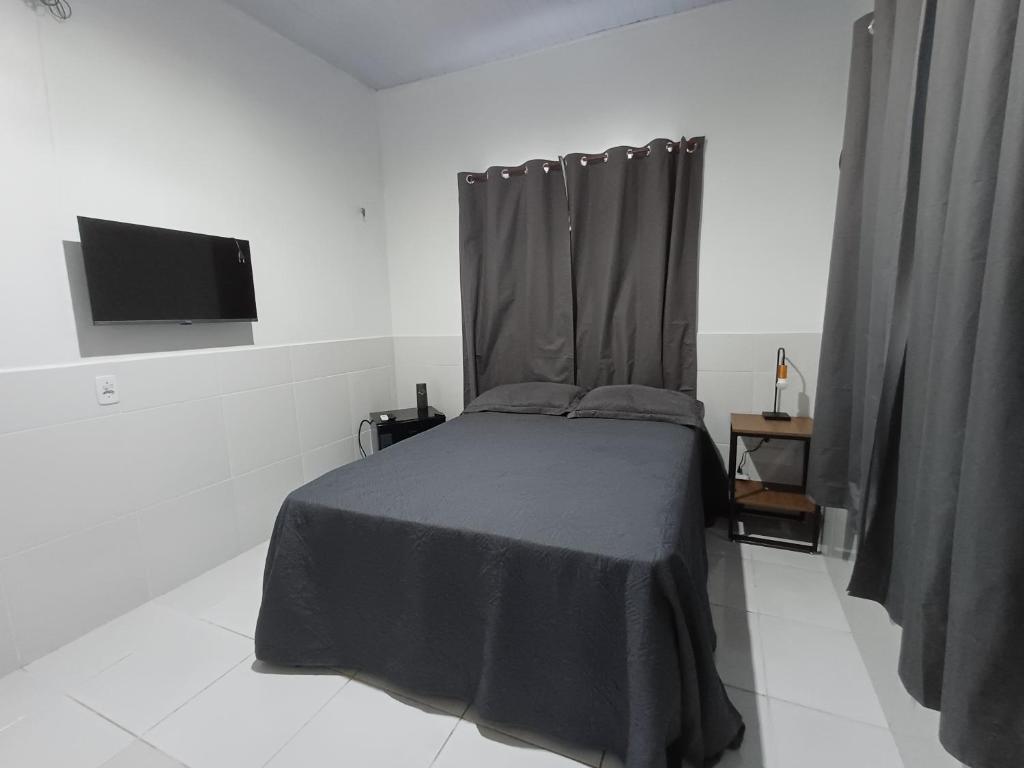 a bedroom with a bed with a black blanket and a tv at Residêncial Fonseca in Juruti