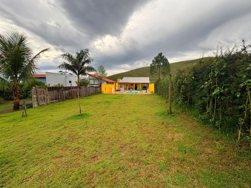 a yellow house in a field with a fence at Chácara Vista do Pico Agudo in Lavrinhas