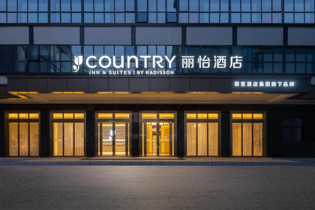 a building with a sign on the front of it at Country Inn & Suites by Radisson Shenzhen International Convention and Exhibition Center in Minzhu