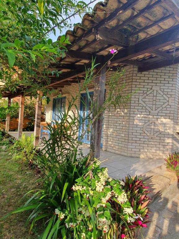 a brick building with a pergola and some flowers at Casa Sol e Mar in Bombinhas