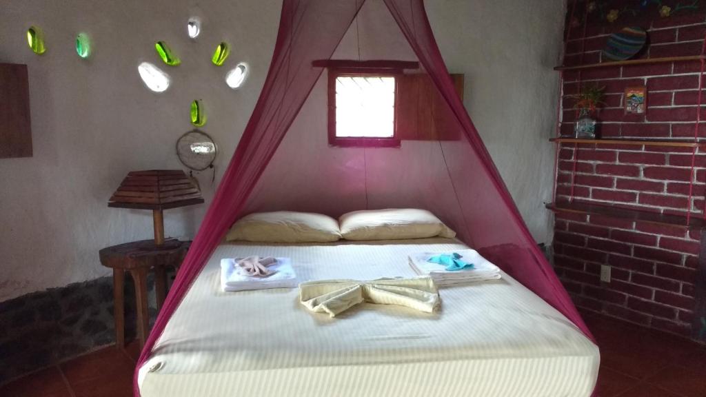Una cama con dosel rojo y toallas. en Finca Mystica en Mérida