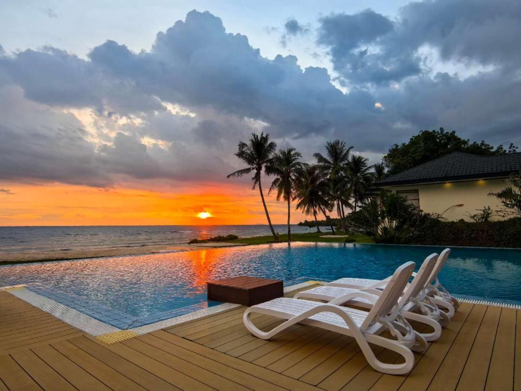 シキホールにあるBlue Joys MSRのラウンジチェア2脚と夕日を望むプールが備わります。
