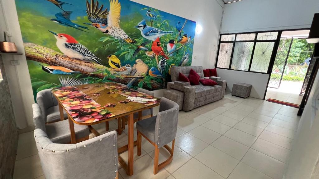 un salon avec une table à manger et un tableau d'oiseaux dans l'établissement My Llano Lindo Américas, à Villavicencio