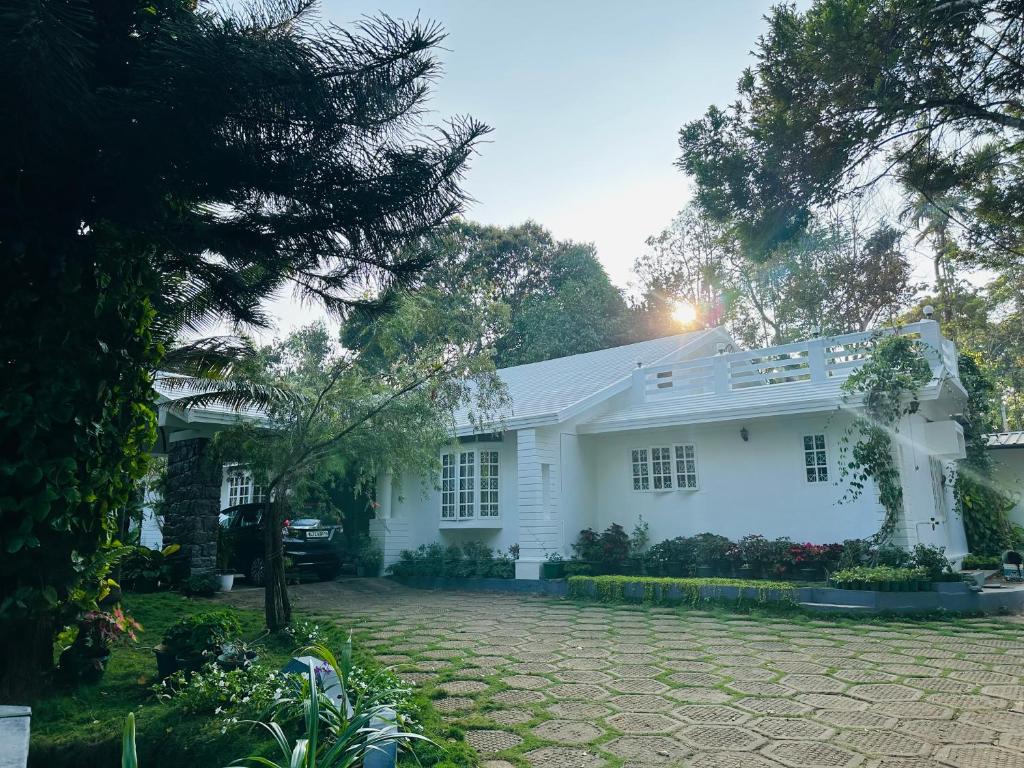 a white house with a driveway in front of it at The Mallika Holidays in Mananthavady