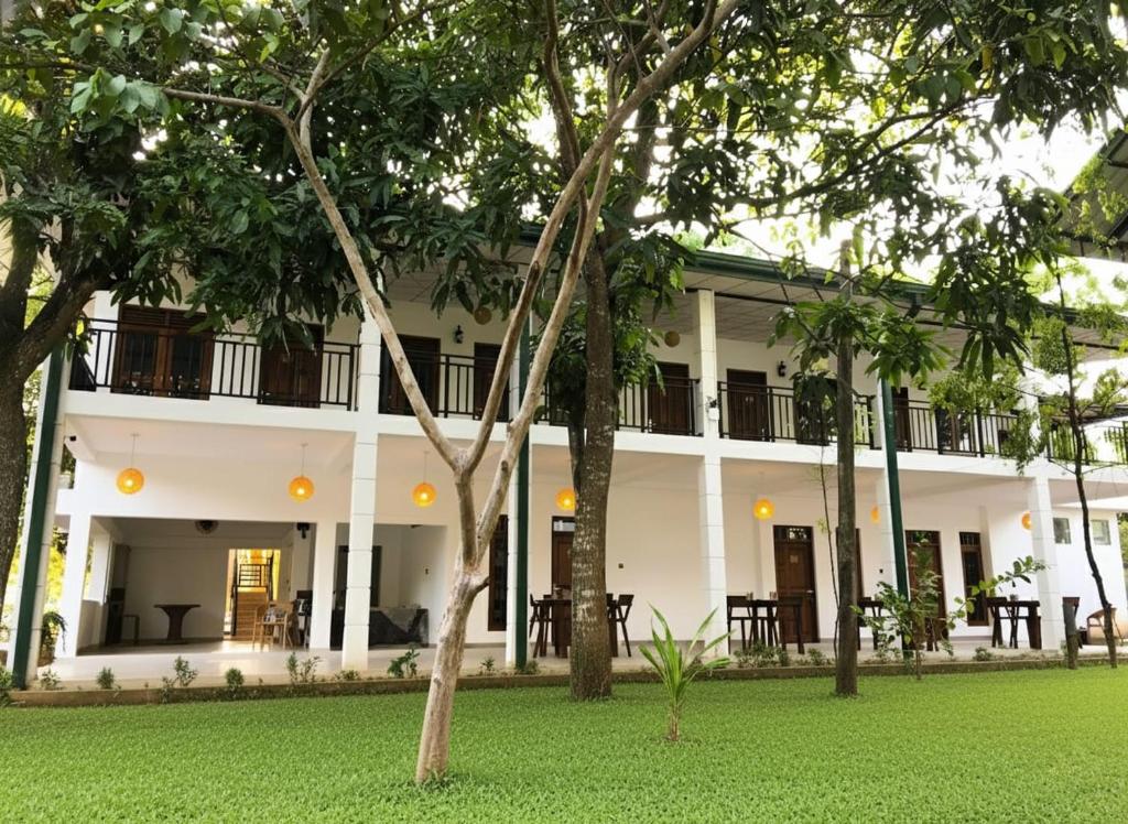 een wit gebouw met bomen ervoor bij The Mammoth udawalawe in Udawalawe