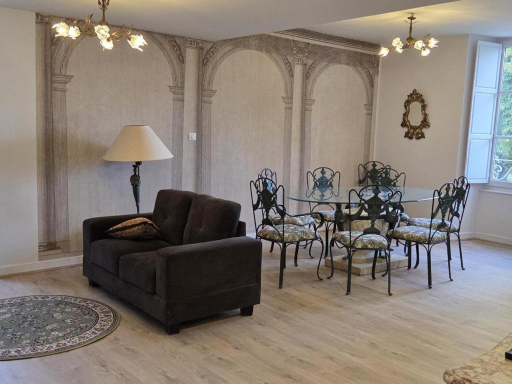 a living room with a couch and a table and chairs at Gîte paisible dans château avec jardin en Auvergne - FR-1-489-604 in Louchy-Montfand